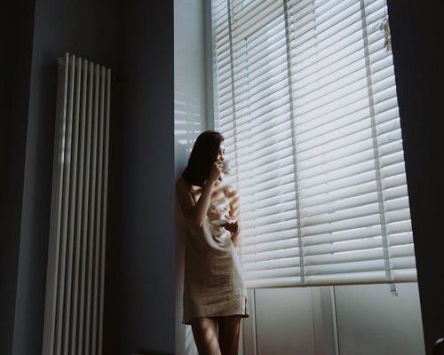 A person enjoying a morning routine with coffee near a window