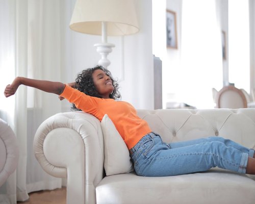 Person relaxing comfortably on a sofa in a brightly lit room